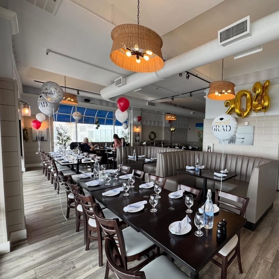 Restaurant dining room set up for a graduation party with balloons, long tables, and booth seating.